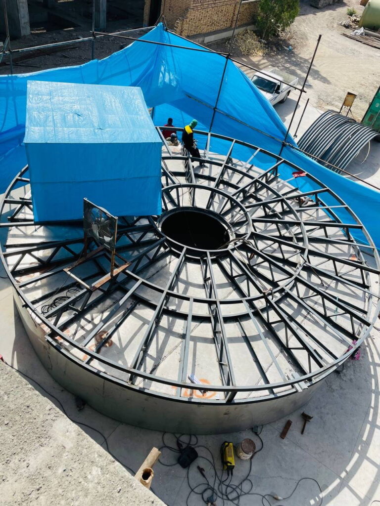 Aerial view of a circular steel frame on the roof of a chemical plant.