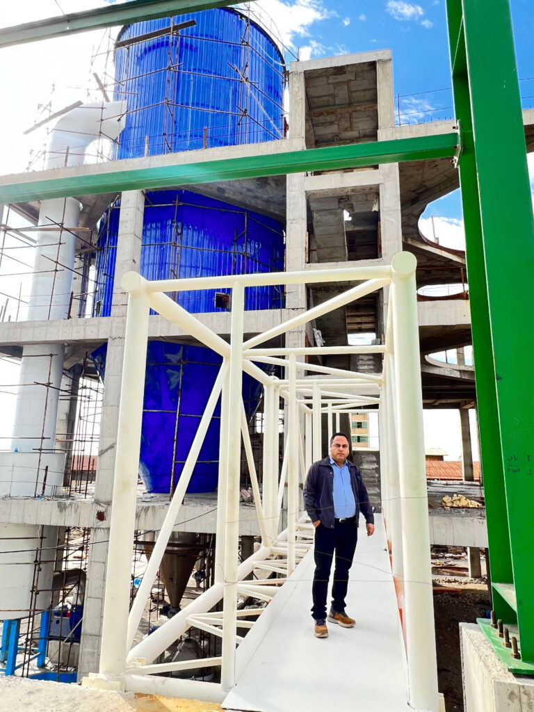 Masood Keneshloo standing on a white steel bridge connecting to a large blue industrial vessel.