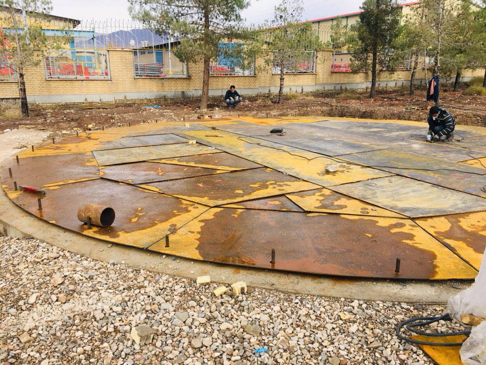 Large circular steel base plates being laid out on a gravel foundation.